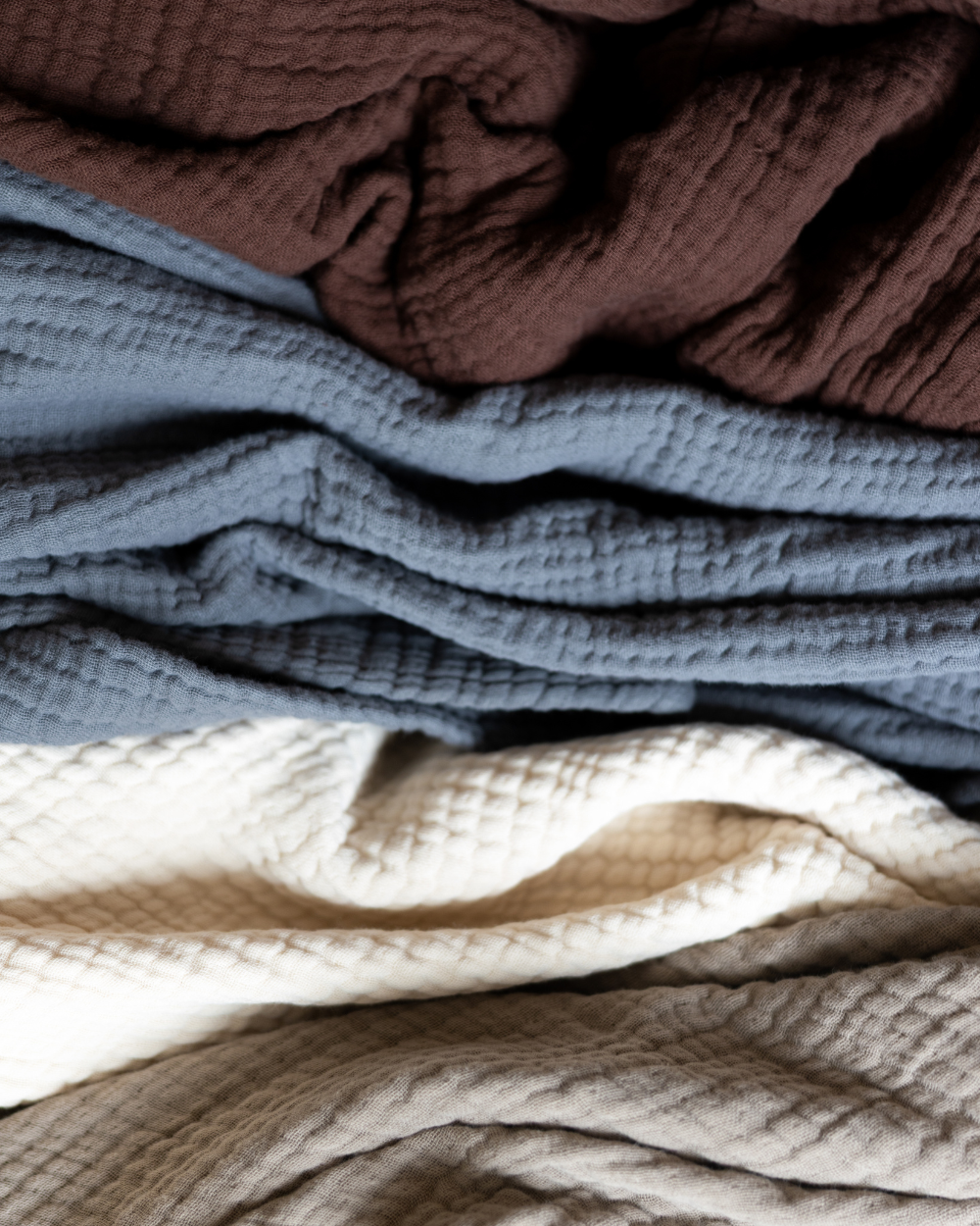 Stack of textured fabric swatches in brown, blue, cream and beige.