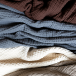 Stack of textured fabric swatches in brown, blue, cream and beige.