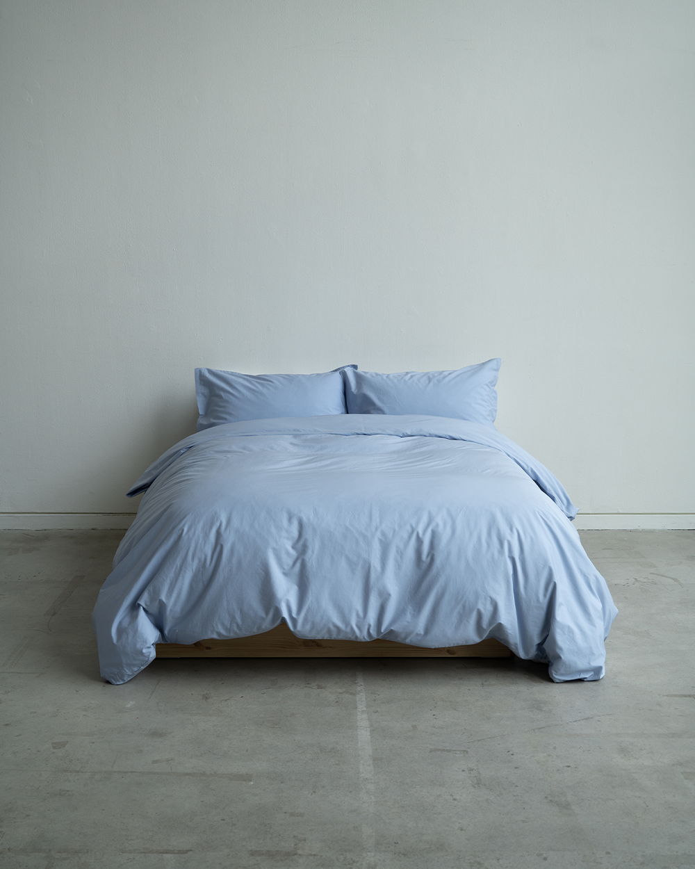 Blue bedding set on a bed against a plain wall.