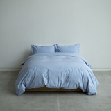 Blue bedding set on a bed against a plain wall.